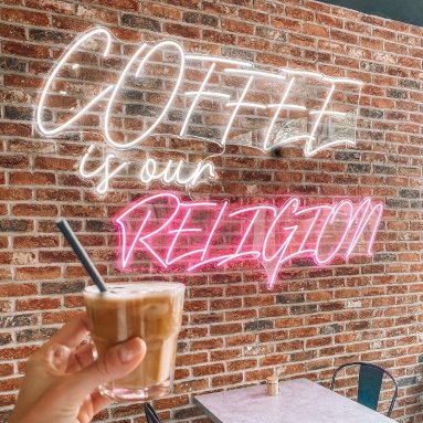 Pink Custom Neon® quote sign Coffee is our Religion on brick wall @mayhapcoffee