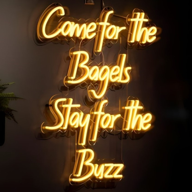 Come for the Bagels Stay for the Buzz yellow Custom Neon® sign on black wall @buzzbagelz