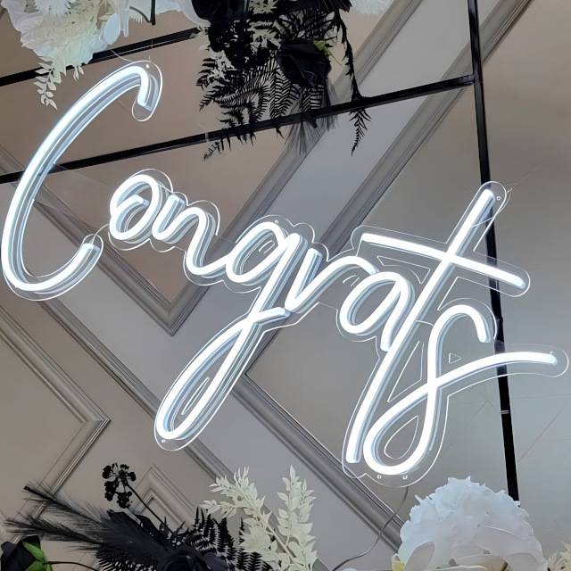 Custom Neon® white Congrats sign on black metal frame surrounded by black and white florals - event decor by @decorandfiesta