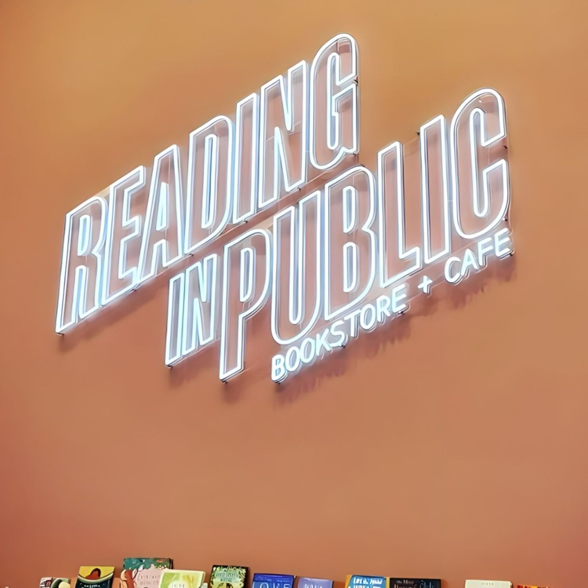 Custom Neon® white LED neon retail sign on orange wall @readinginpublicbooks