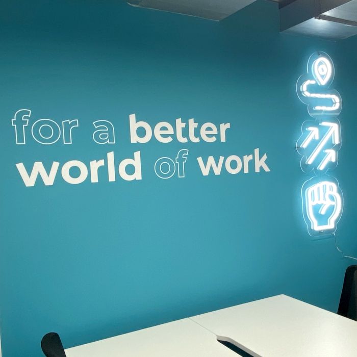 White LED neon brand art on a light blue wall in the offices of @talent_international