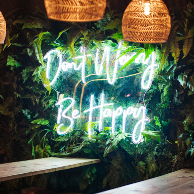 Don't Worry Be Happy Custom Neon® quote sign on a green wall