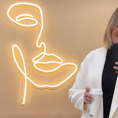 Warm white Custom Neon® line art of a woman's face in a beauty salon