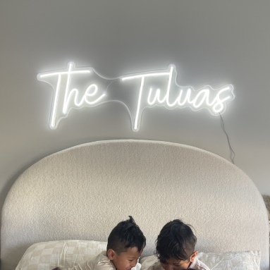 Custom Neon® white family name sign on a white wall above a bed @the.tuluas