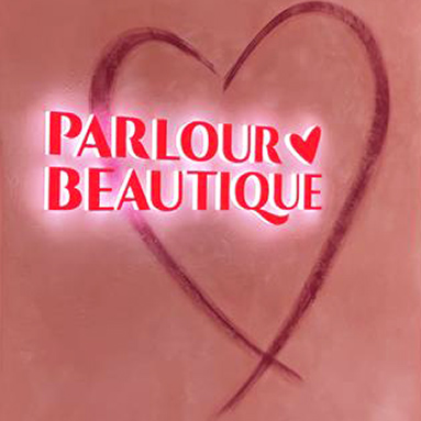 Parlour Boutique 3d acrylic logo with a red face fully lit in white LED light on a pink wall