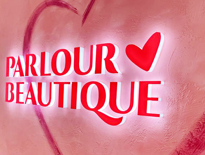 A photograph of a beauty salon's fully illuminated logo sign