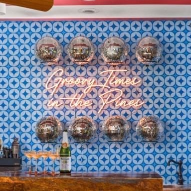 Custom Neon® orange sign reading Groovy Times in the Pines on a blue tiled wall in a home bar @somerleddesigns