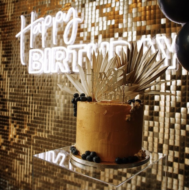 White Custom Neon® Happy Birthday sign on a golden shimmer wall styled by @raspberrycraftsandevents