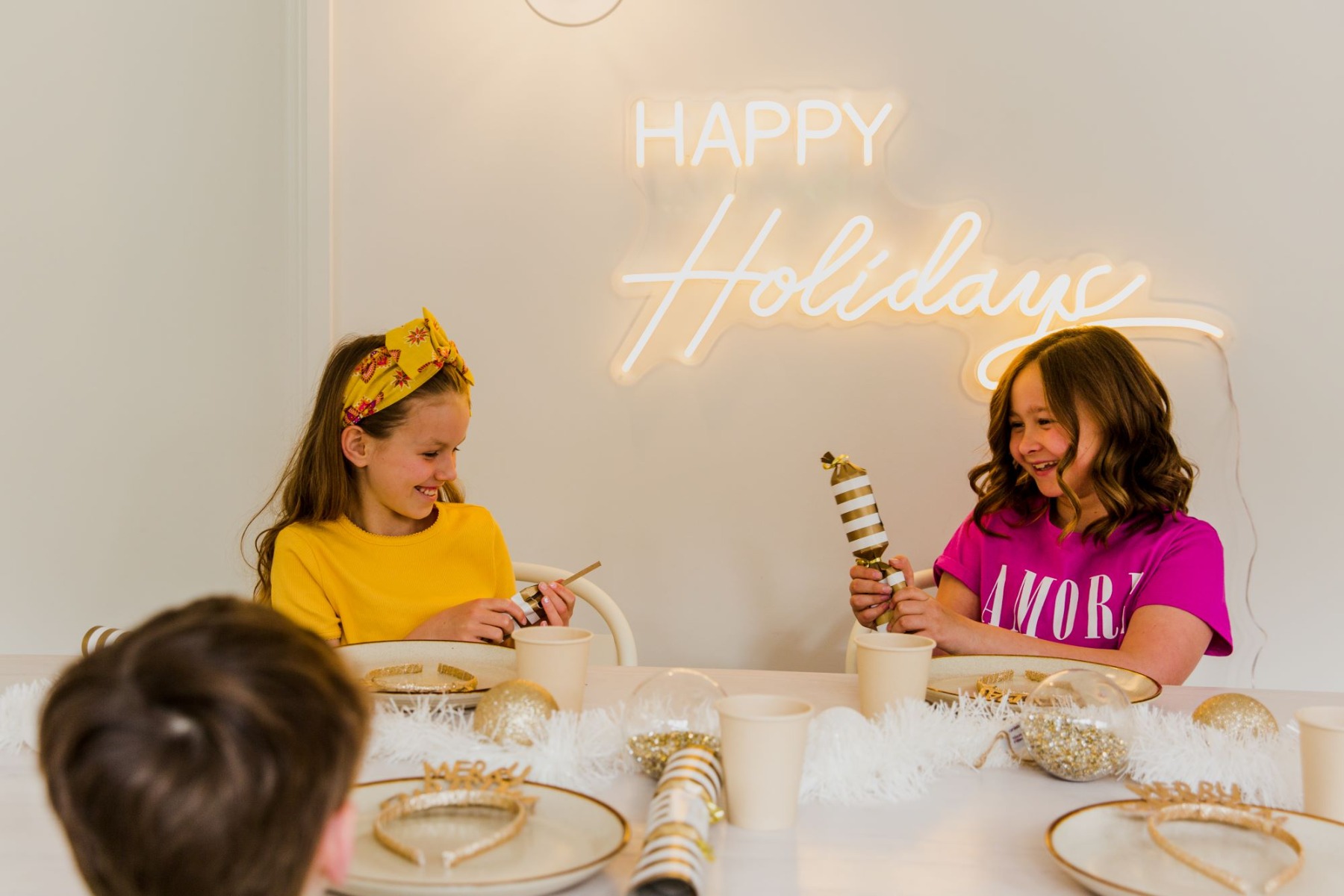 Custom Neon® Happy Holidays festive wall sign above the dining room table during a family Christmas dinner