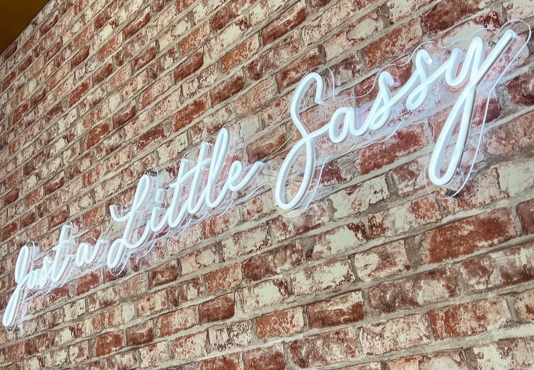 Just a Little Sassy Custom Neon® white selfie sign on brick wall installed by @czar_electrical