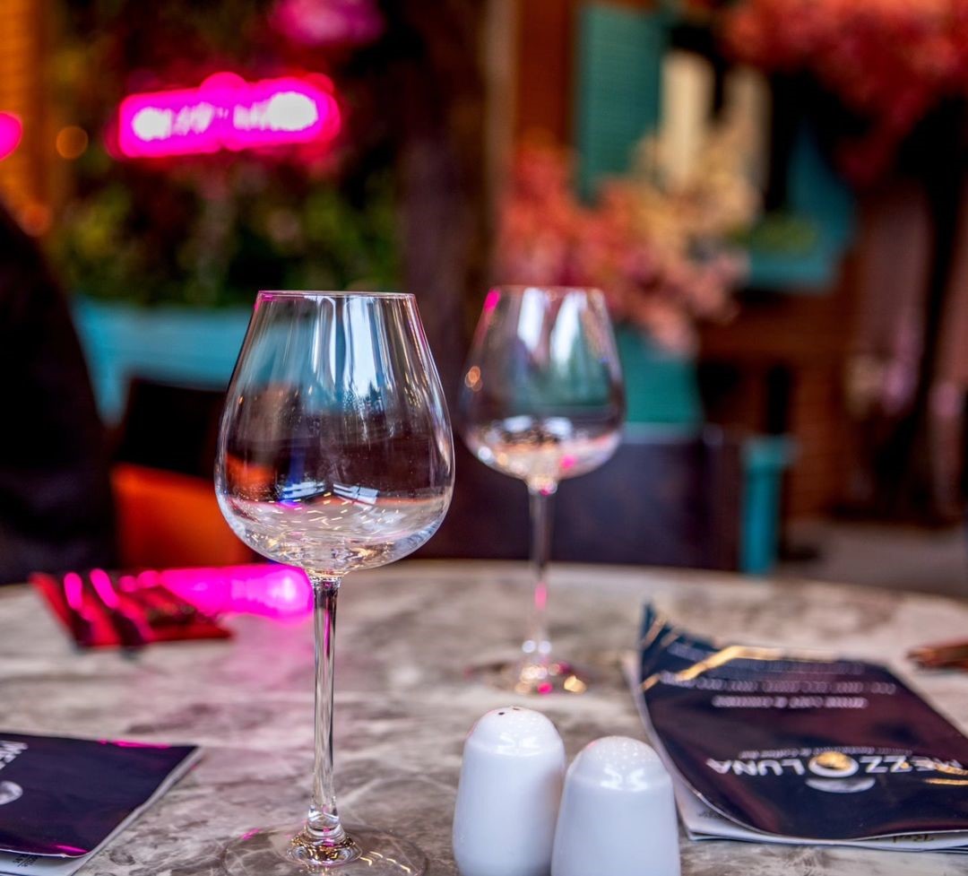 Custom Neon® pink restaurant name sign in the background @mezzalunabristol