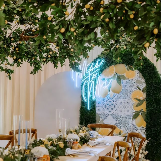 Custom Neon® white Miss to Mrs sign affixed to green arch with a fresh lemon motif styled by @decorandfiesta