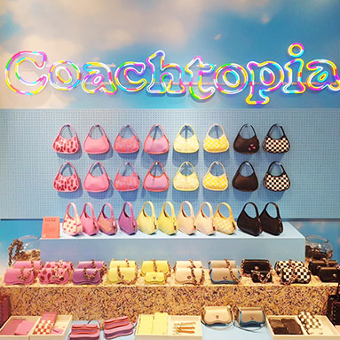 Custom Neon® colorful no-waste LED neon Coachtopia logo sign hanging above a display of Coach handbags