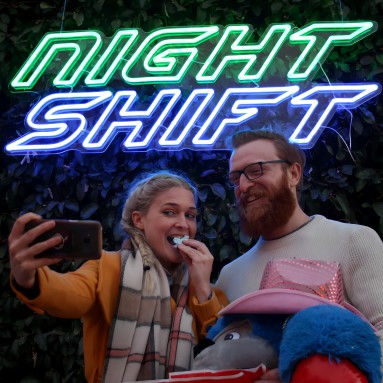 Custom Neon® blue and white festival sign on a greenwall with festival goers taking a selfie