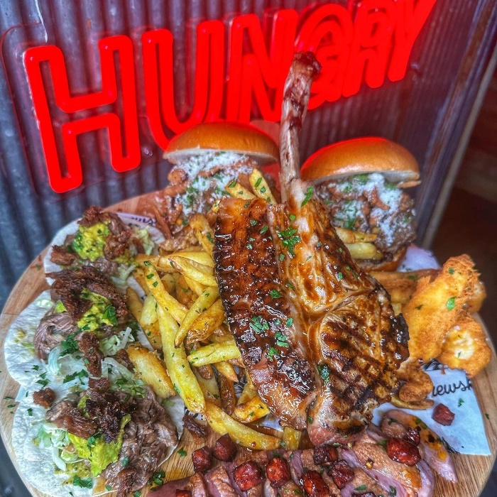 Nobody leaves hungry red double-lined Custom Neon® sign on corrugated metal wall with plate of food in the foreground @brewskichorlton