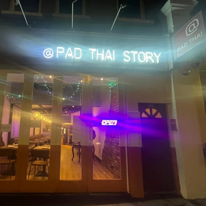 Pad Thai Story white Custom Neon® exterior sign above the entrance to the Pad Thai Story restaurant