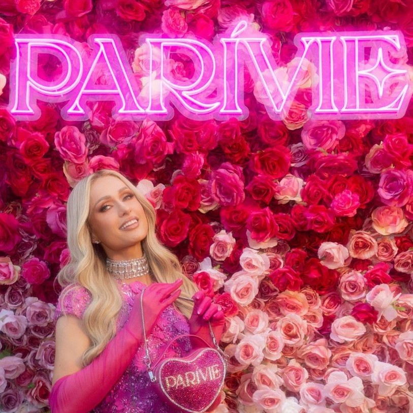 Custom Neon® pink Parivie logo sign on a rose wall with Paris Hilton in the foreground