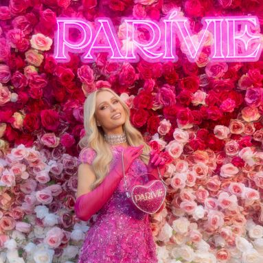 Parivie pink sign made by Custom Neon® on a rose wall selfie backdrop with @parishilton in the foreground