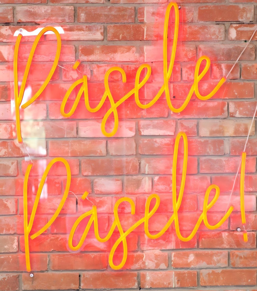 Custom Neon® red Pásele Pásele! sign on a red brick wall @onetacoaustin