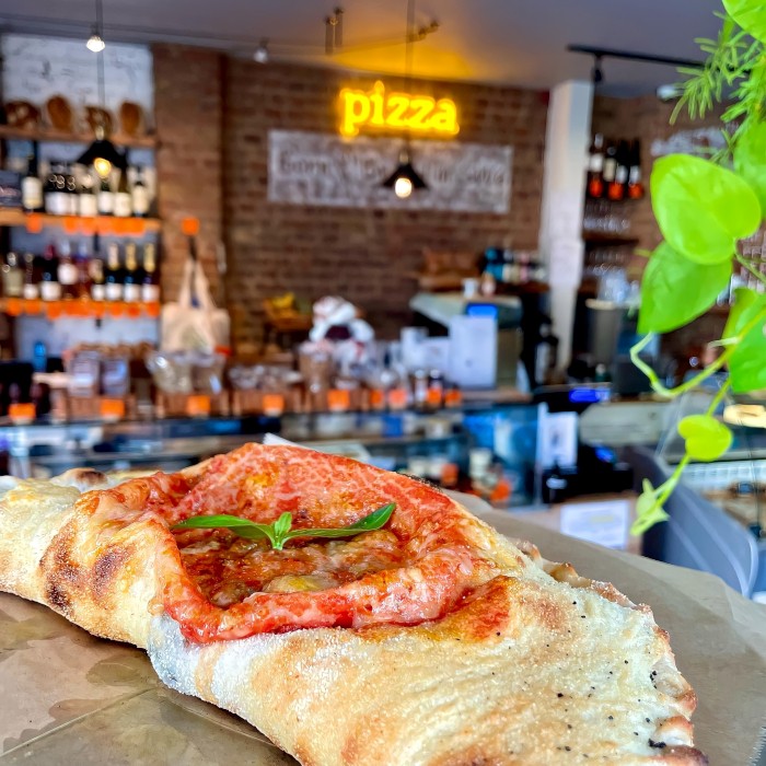 Pizza orange Custom Neon sign on a brick wall above a calzone @bridge_baker