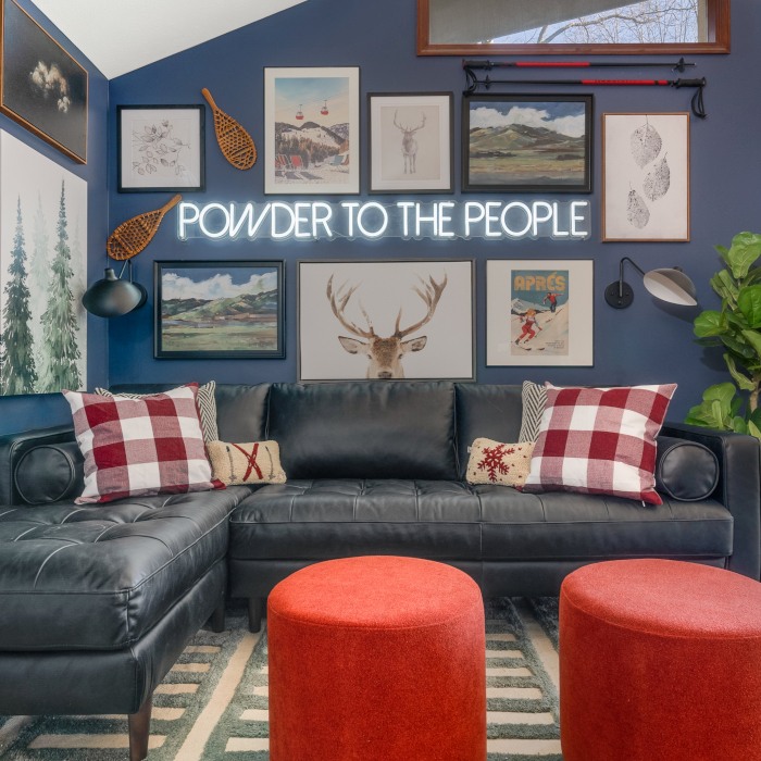 Powder to the People large white LED Custom Neon® sign on a blue feature wall surrounded by framed ski resort inspired prints in an Airbnb cabin designed by Somerled