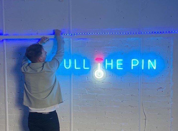 Blue Custom Neon® company name logo sign on white wall @pullthepinagency