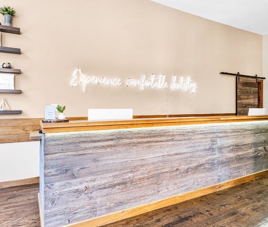 White Custom Neon® Experience Comfortable Dentistry sign behind reception @puredentalspa