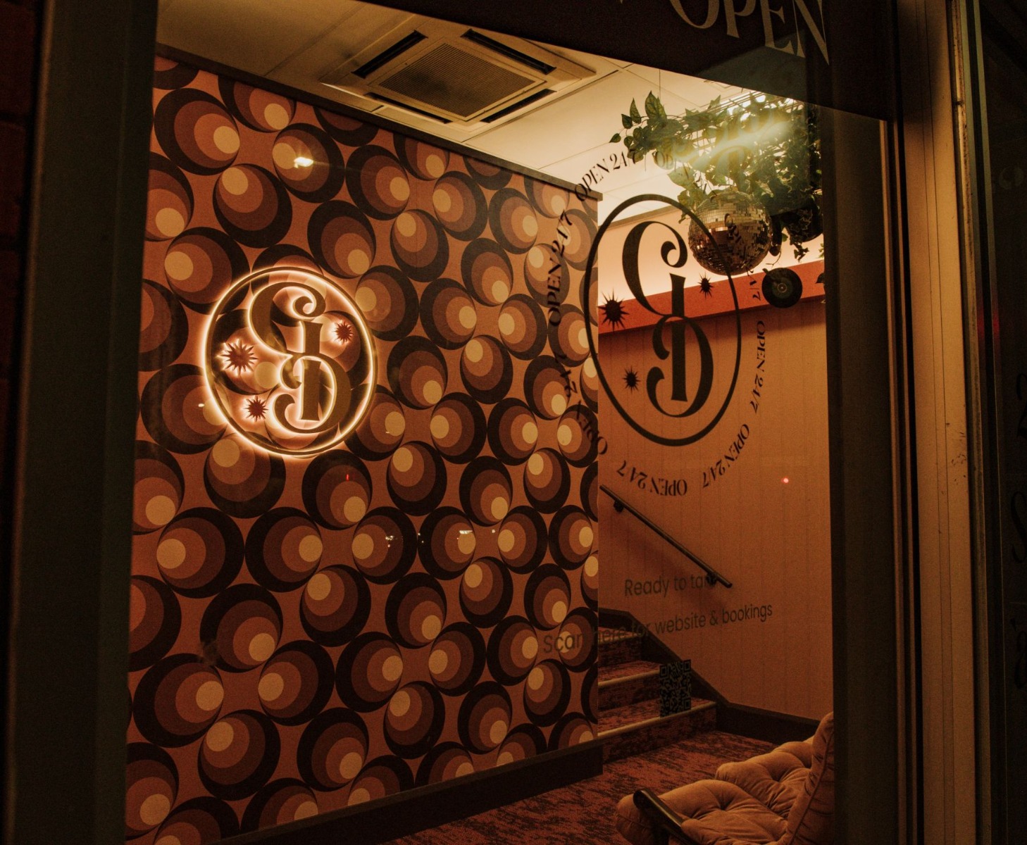 Gold coloured stainless steel reverse lit logo made by Custom Neon® on a 70s inspired wall in the Golden Days tanning salon as seen through the salon's front window