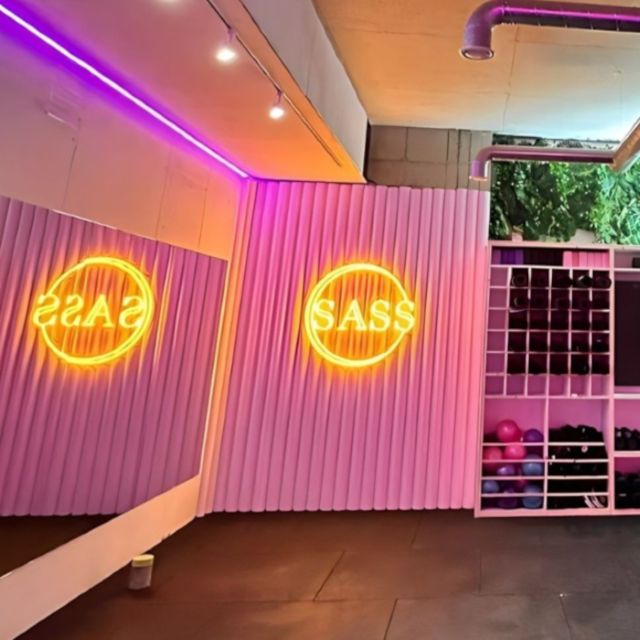 SASS yellow Custom Neon® logo sign on the wall of the @sculptsweatstudio