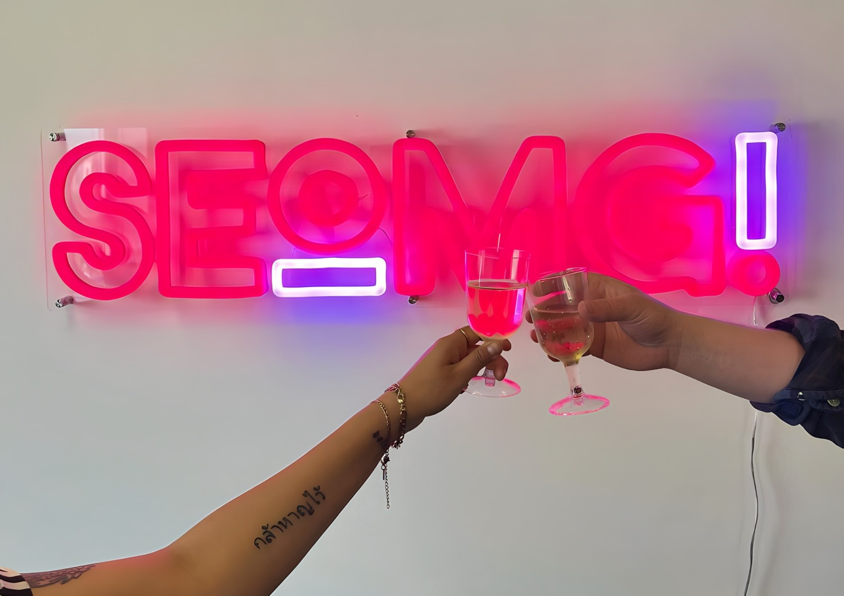 Custom Neon® pink and purple company logo sign on white office wall @seomg_agency