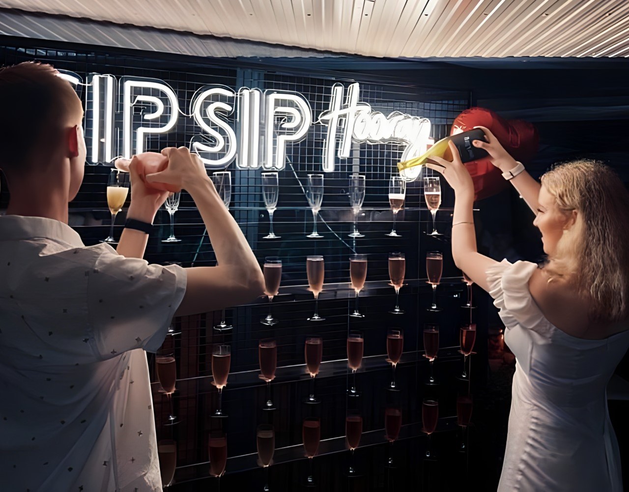 SIP SIP Hooray white Custom Neon® sign attached to a wire mesh frame above champagne glasses @tothewallhire