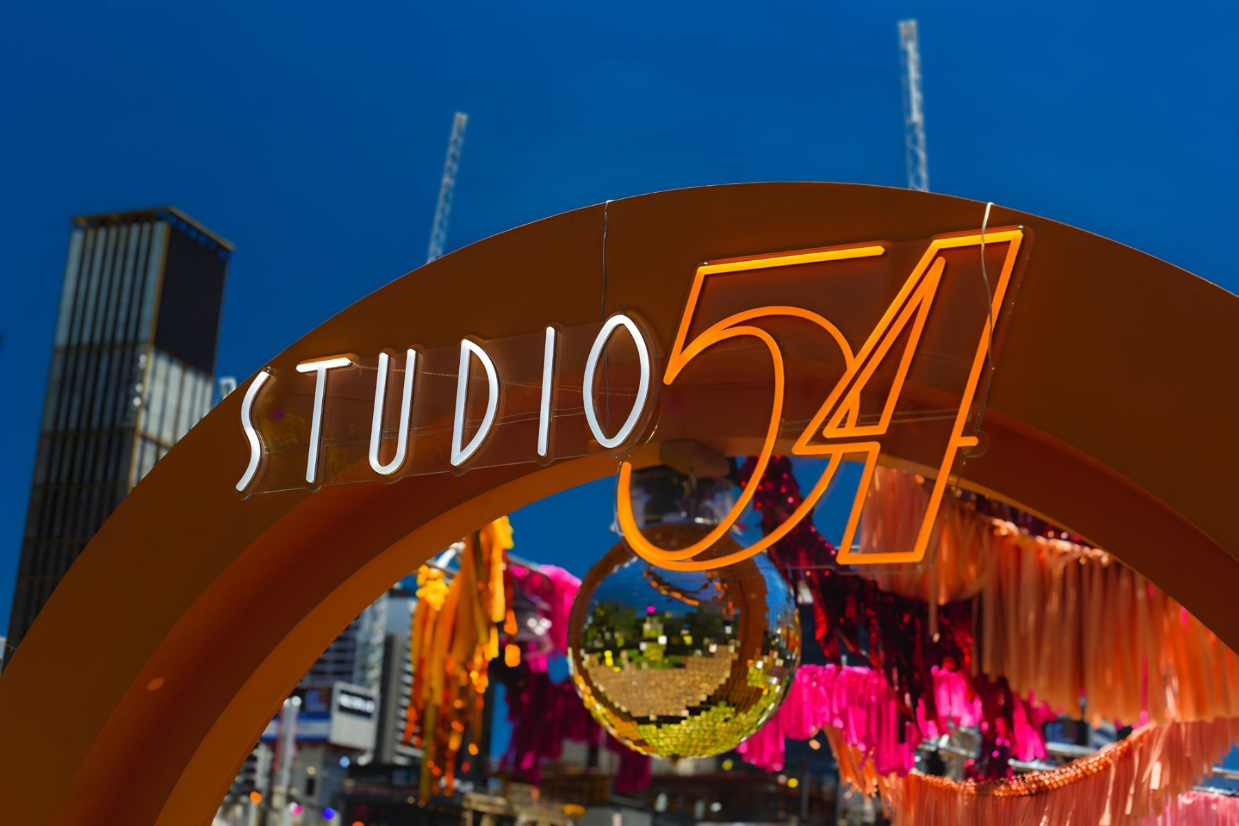Weatherproof Custom Neon® white and orange Studio 54 sign on an arch at the entrance to the Disco Fever corporate party organized by @ultimo_catering