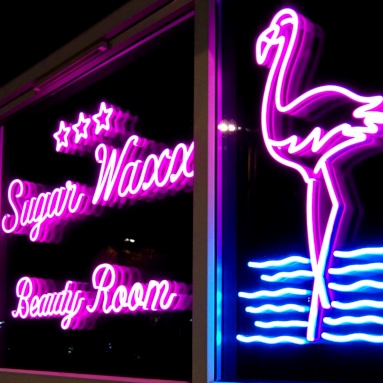 Custom Neon® large pink and blue window sign of flamingos on water with the Sugar Waxx logo @sugarwaxx