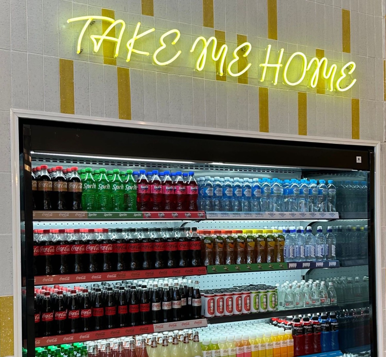 Custom Neon® yellow Take Me Home retail signage above a beverage fridge @thelittlespoonco