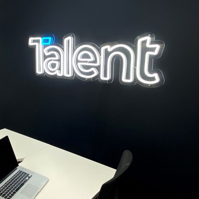 Custom Neon® office logo sign for Talent International in white LED neon on a black wall