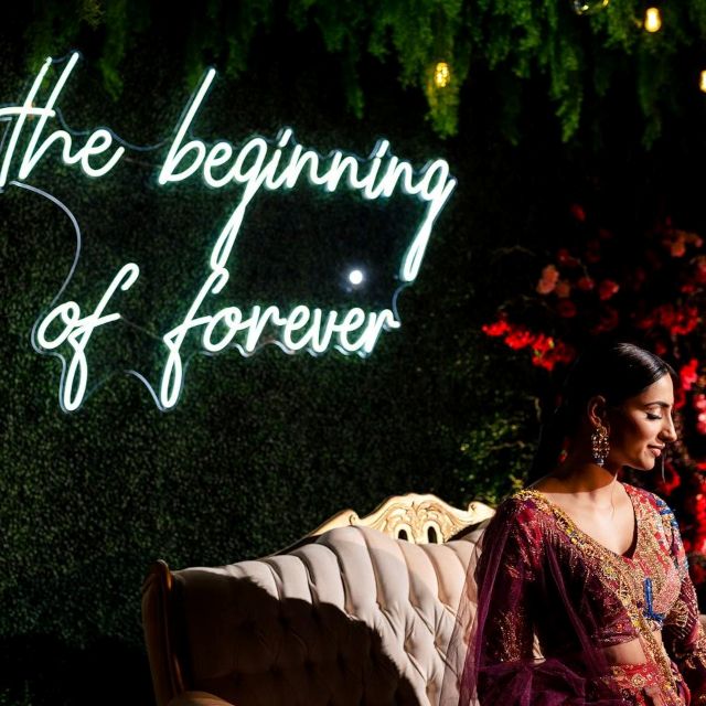 The Beginning of Forever white Custom Neon® wedding quote sign on a grass wall behind the selfie couch photography by @moorephotography