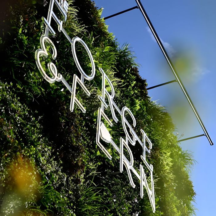 Outdoor restaurant Custom Neon® F logo sign on green wall @theforgeandfern