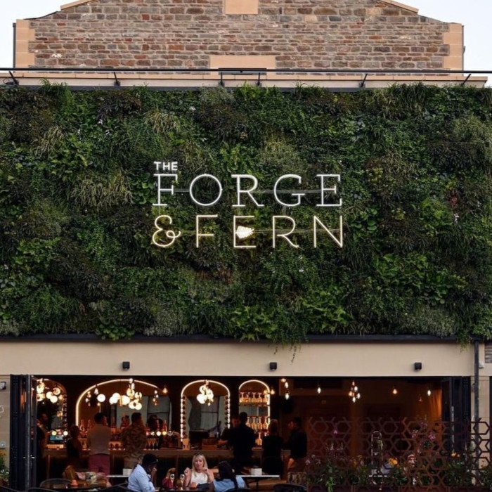 Large Custom Neon® waterproof logo sign on a green wall @theforgeandfern