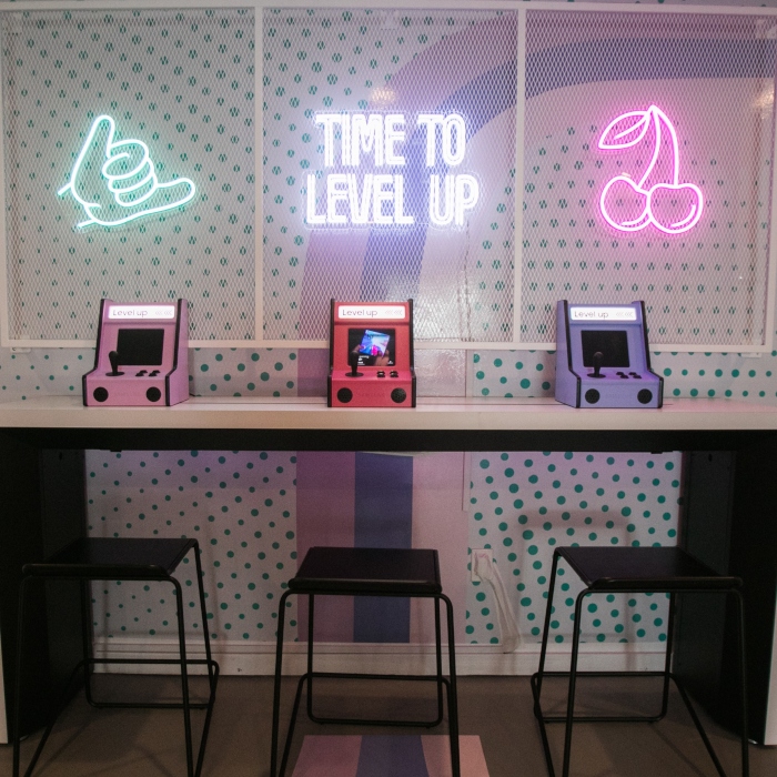 Time to Level Up and emoji Custom Neon® signs behind the tabletop video game machines in the Samsung Flip Side Pop-Ups