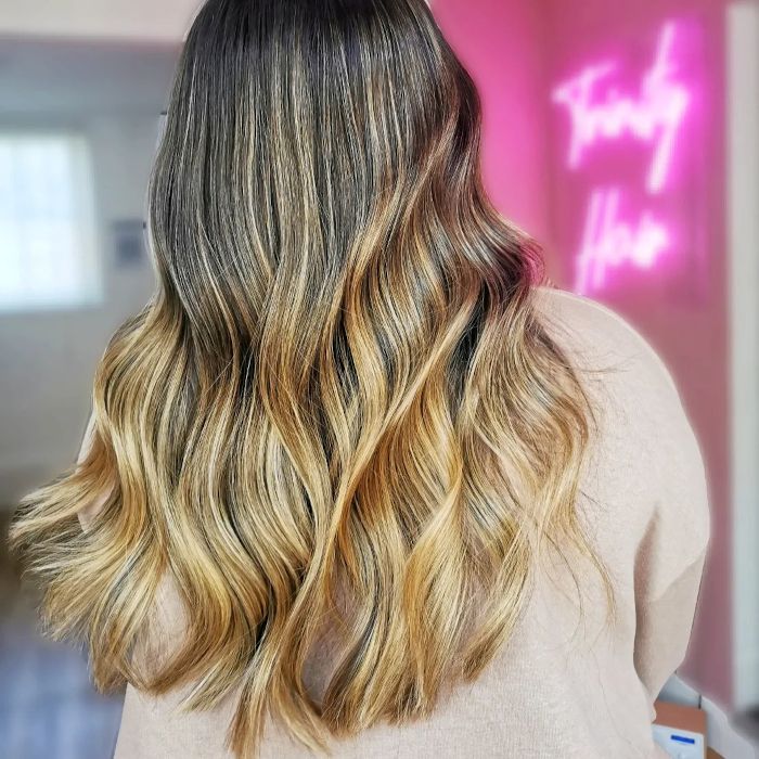 Woman in front of a pink Custom Neon® sign reading Trinity Hair