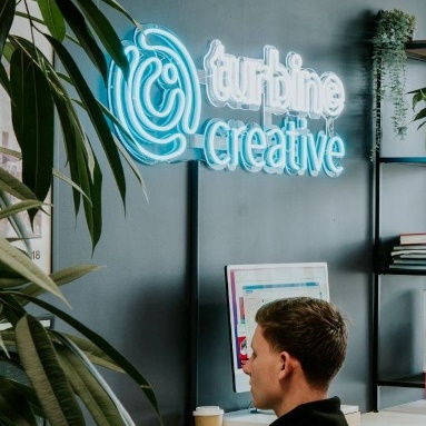 Custom Neon® light blue logo sign in the office @turbinecreative_