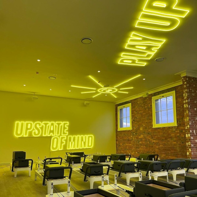 Custom Neon® yellow gym signage mounted on the ceiling and walls @upstate_studios