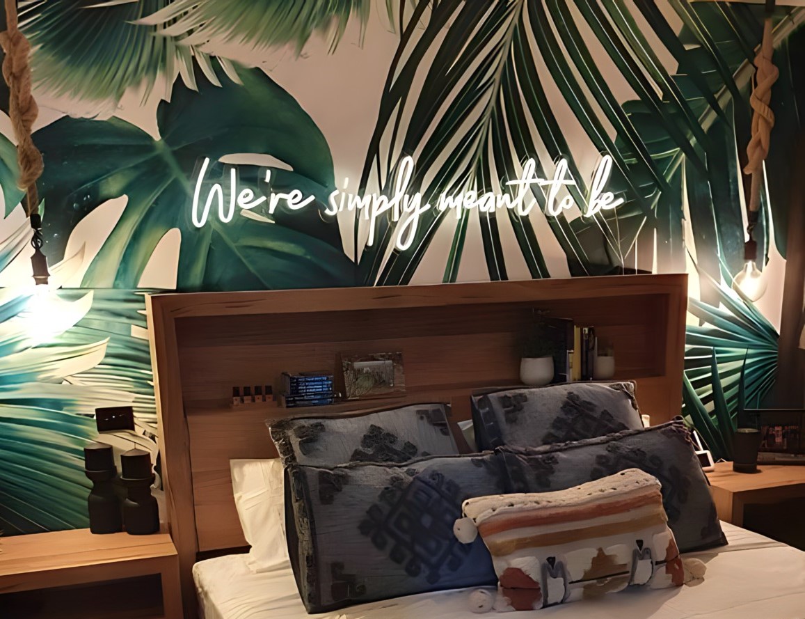 Custom Neon® white quote sign above a bed against tropical wallpaper
