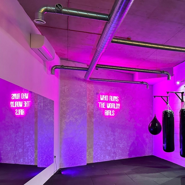 Who Runs the World pink double lined Custom Neon® lyric sign reflected in the mirror @sculptsweatstudio