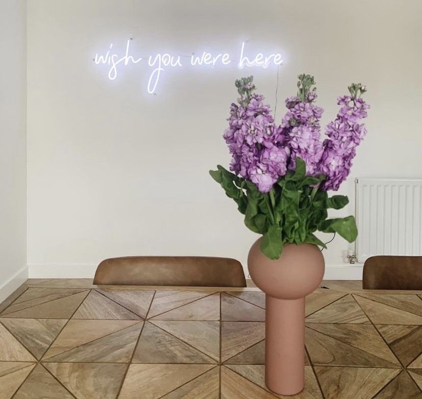 Wish You Were Here white Custom Neon® sign installed on a white wall in a dining room @livingeastside