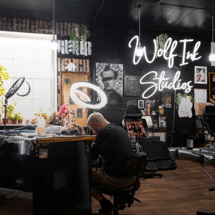 Large white Custom Neon® tattoo studio name sign on a black wall @wolf_ink_studios in Exeter