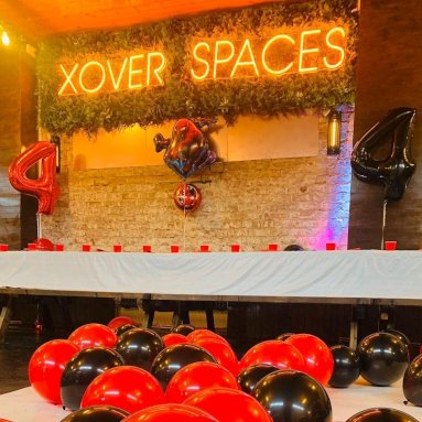 Orange Custom Neon® event venue name sign above tables set with party decorations @xoverspaces