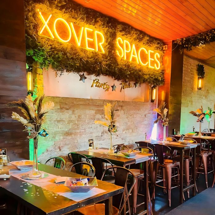 Orange Custom Neon® event venue name sign above tables set with party decorations @xoverspaces