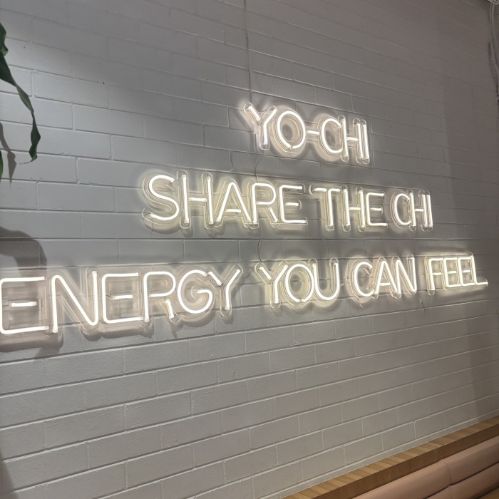 Yo-Chi tagline sign made by Custom Neon&reg; in warm white LED neon on a white brick wall @iloveyochi
